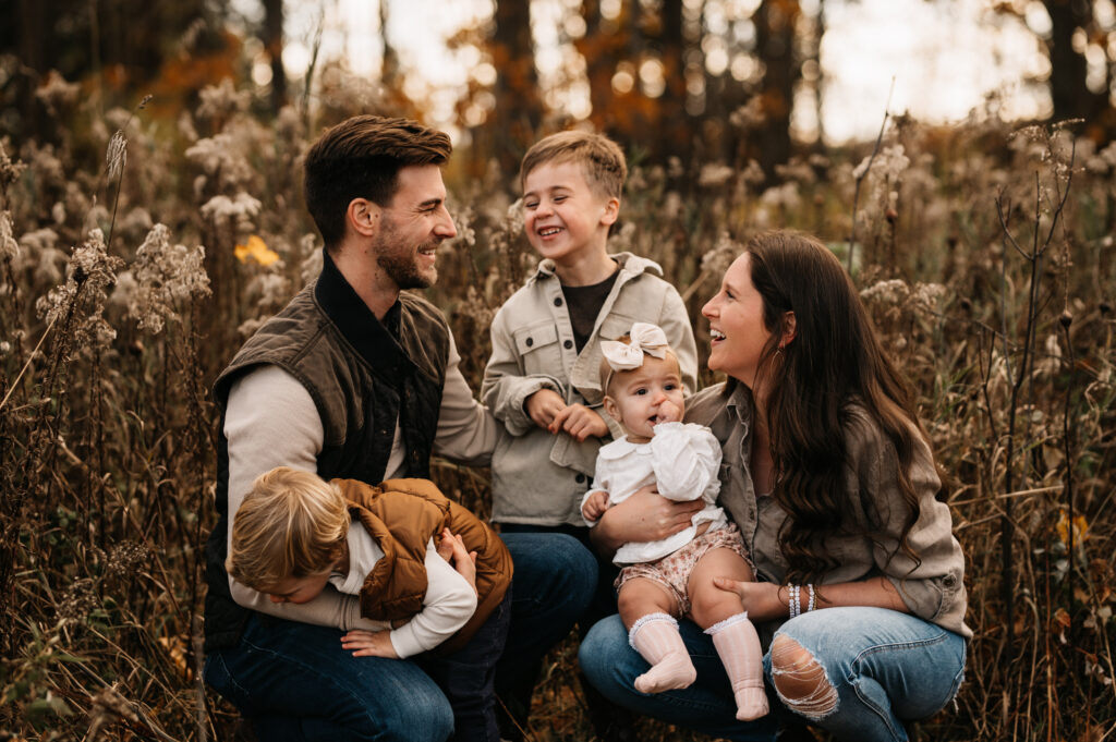 Wyatt, Jessi, and their three kids laughing in a field